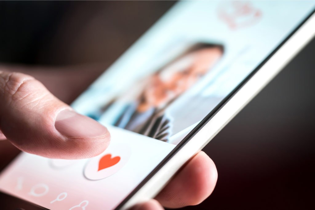 Two people smiling at their smartphones while using a dating app
