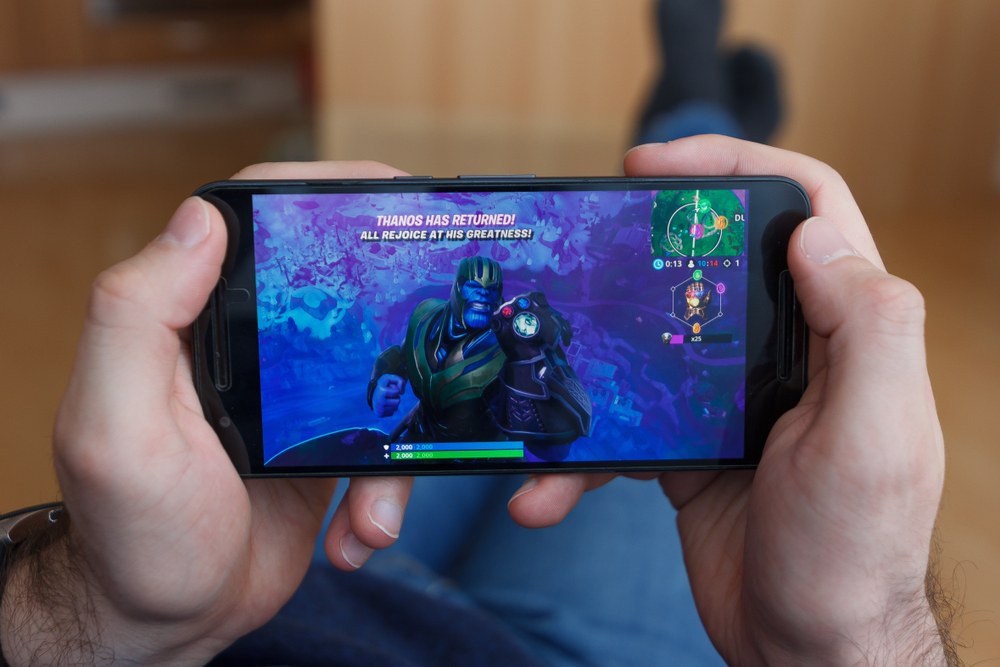 Mobile gamer holding a smartphone with games on screen