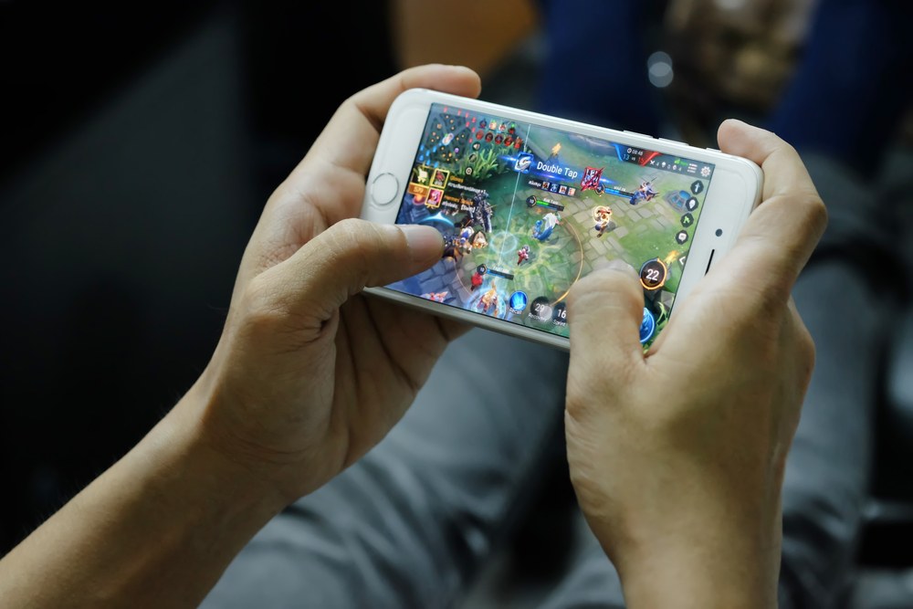 Person playing an action game on a mobile phone
