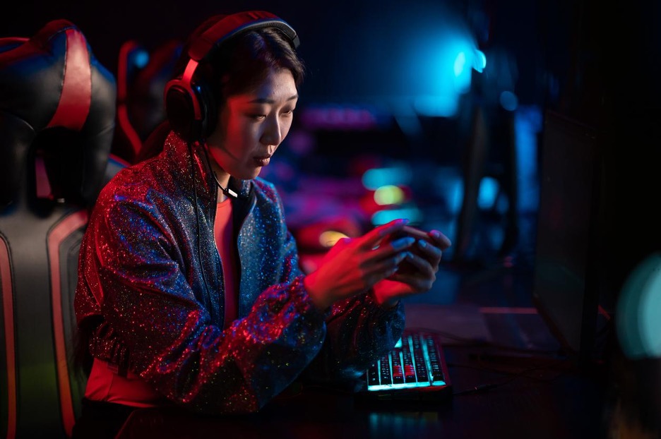 woman-holding-a-smartphone-in-a-computer-club-playing-mobile-games